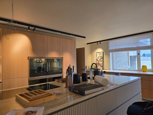 Moderne Küche mit Holzschränken, Kochausrüstung und Fenster mit Blick nach draußen.